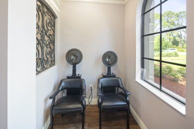 A small salon area with two chairs and hair dryers under a window.