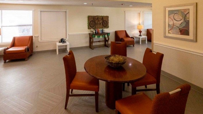 A cozy living space with a round wooden table surrounded by chairs, accentuated by artwork and ambient lighting.