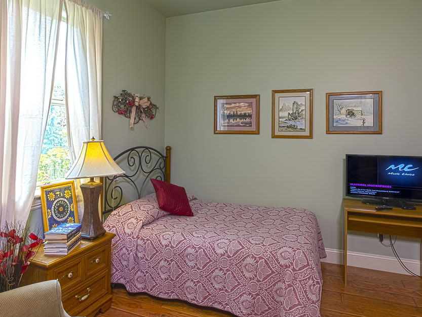 A cozy bedroom with a patterned bedspread, wall art, and natural light.