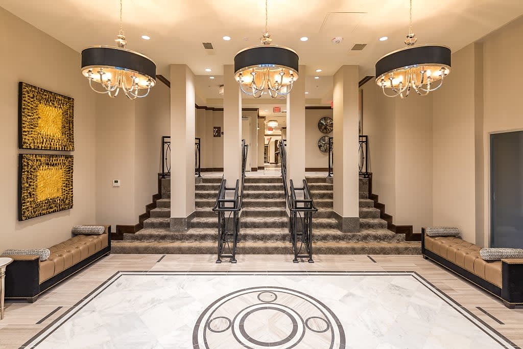 An elegant hotel lobby featuring grand staircases and ornate chandeliers.
