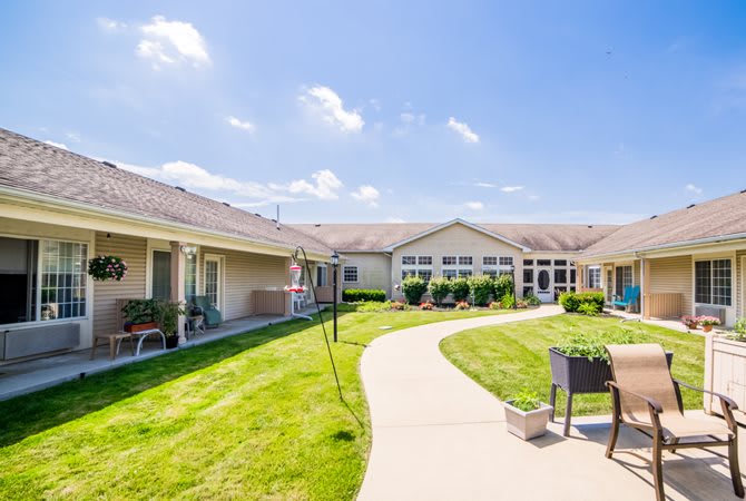 A sunny courtyard with a meandering pathway and well-maintained lawn, surrounded by residential buildings.