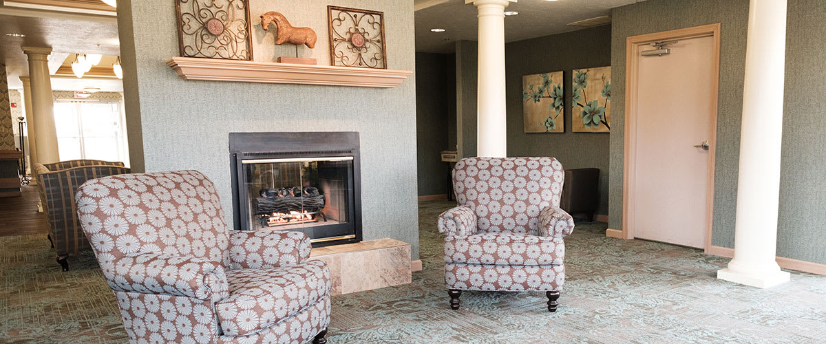 A cozy living room with patterned armchairs and a fireplace.