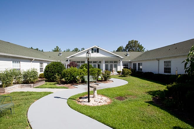 A well-maintained building with a surrounding lawn and pathway on a clear day.