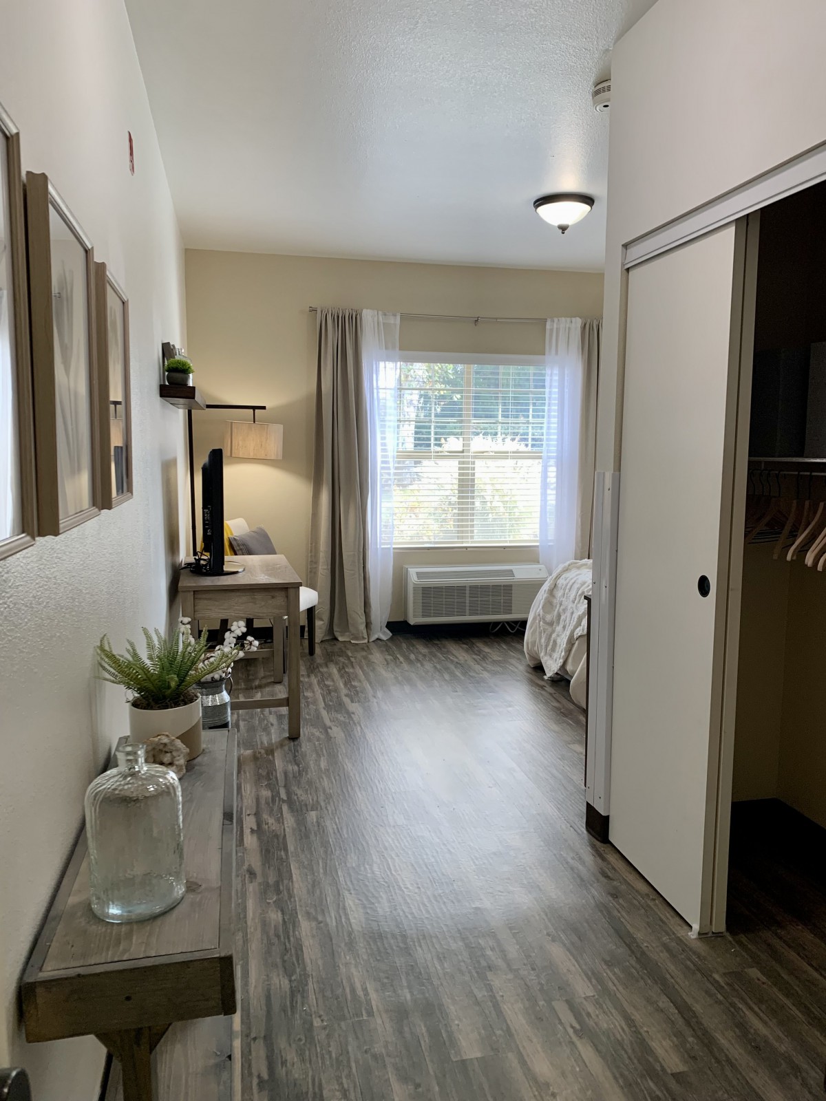 A modern and minimalist bedroom interior with sleek flooring, stylish decor, and natural lighting from a large window.
