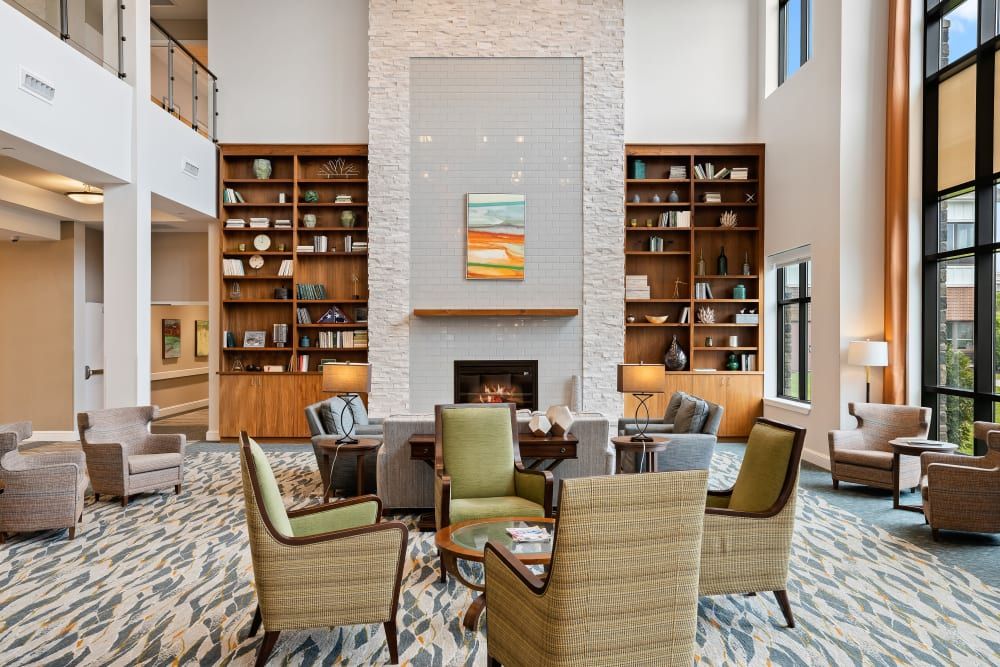 A modern library with a cozy seating area, featuring bookshelves and a central fireplace.