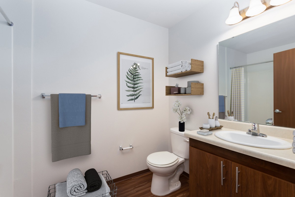 A neatly organized bathroom with a modern design featuring a sink, toilet, and decorative elements like wall art and plants.