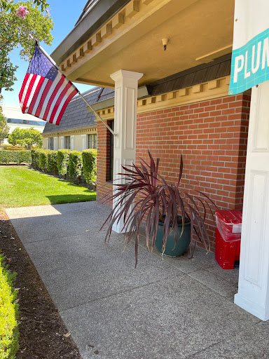 An inviting entrance featuring an American flag, colorful plants, and a well-maintained sidewalk.