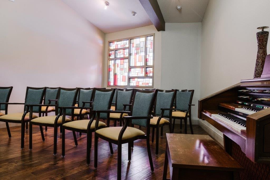 An empty room with several chairs lined up on a wooden floor, facing a window.