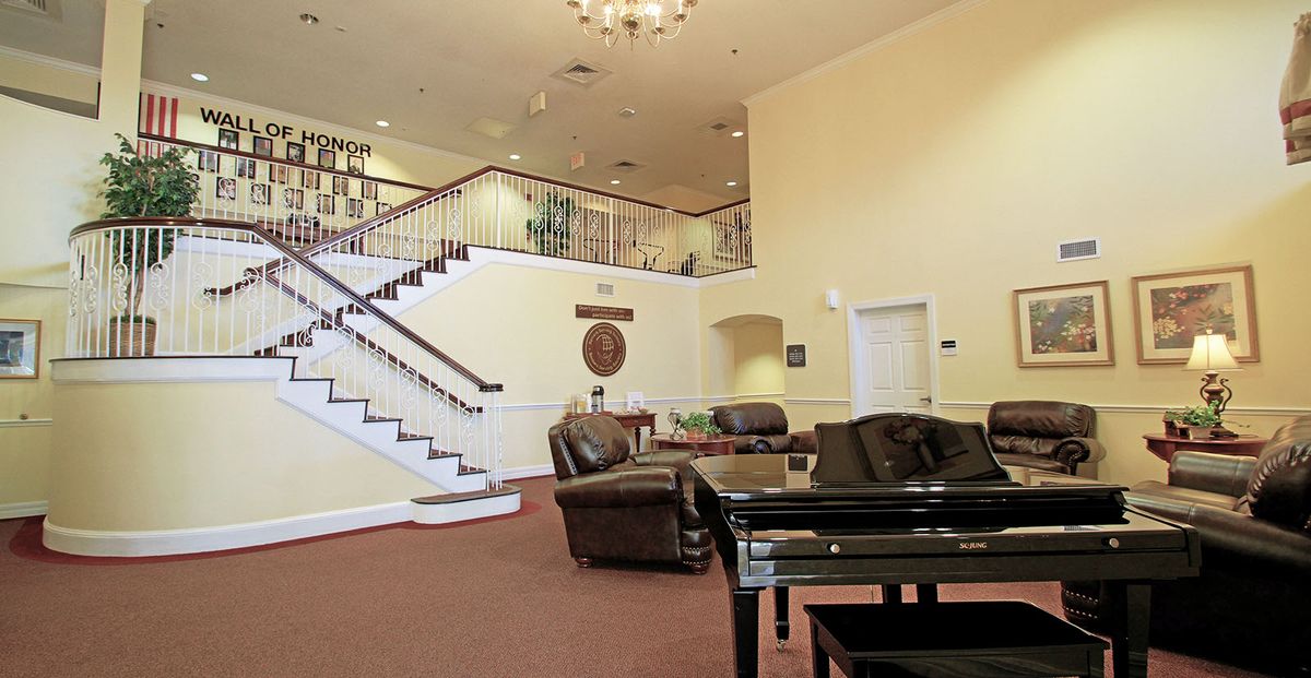 A spacious lobby with a grand staircase, comfortable seating, and a grand piano.