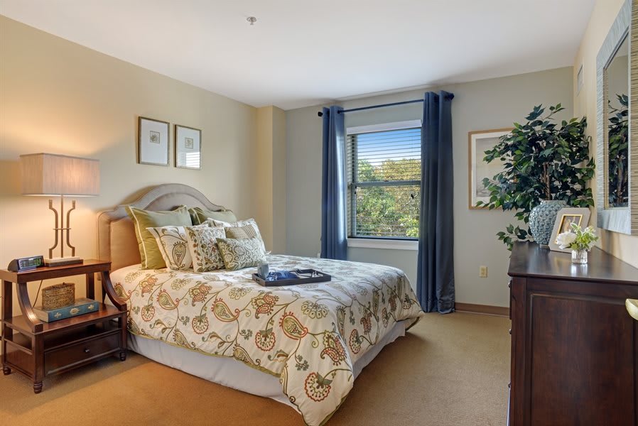 A cozy bedroom with elegant bedding, a scenic view through the window, and tasteful decor.