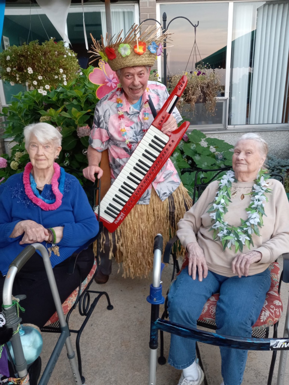 A lively scene with seniors enjoying a tropical-themed gathering, featuring leis and music in a garden setting.
