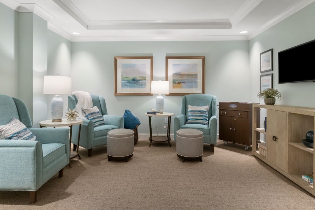 A cozy living room with blue armchairs, ottomans, and soft lighting.