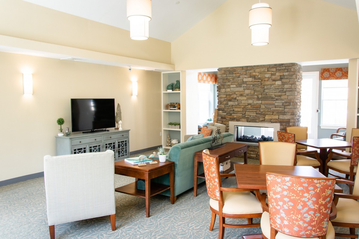A modern living room featuring a cozy sitting area, dining table, and stone fireplace.
