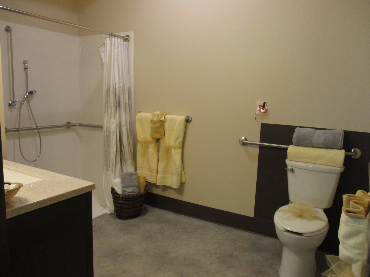 An accessible bathroom with a shower, toilet, and towels.