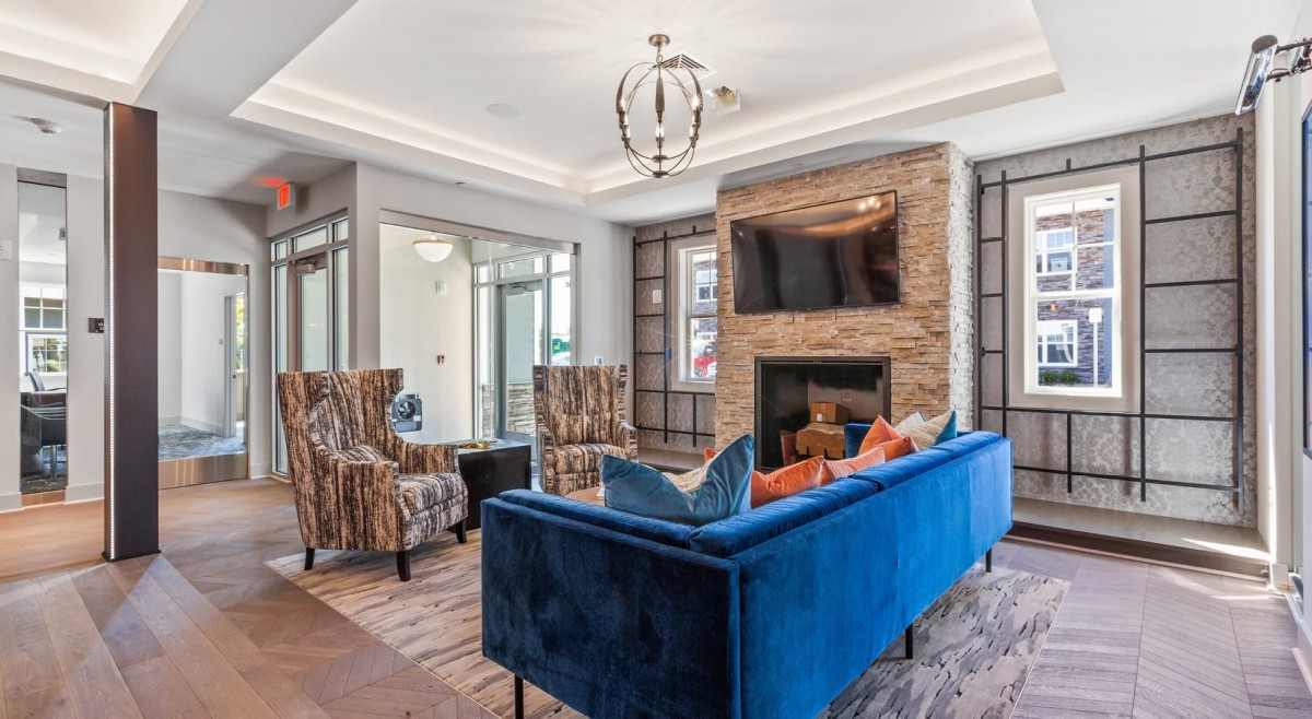 A modern living room with a blue sofa, stone fireplace, and stylish decor.
