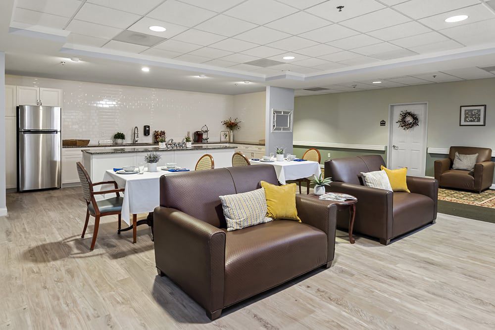 A modern living room with comfortable leather couches and a dining area in the background.