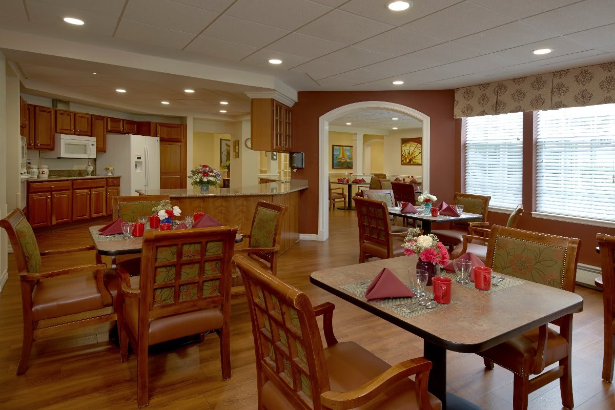 A cozy dining area with neatly arranged tables and chairs, featuring warm lighting and decorative elements.
