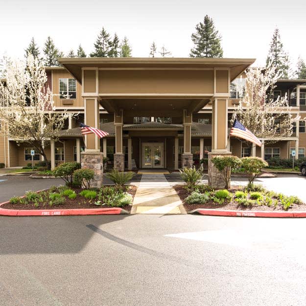 A well-maintained building entrance with surrounding trees and landscaping.