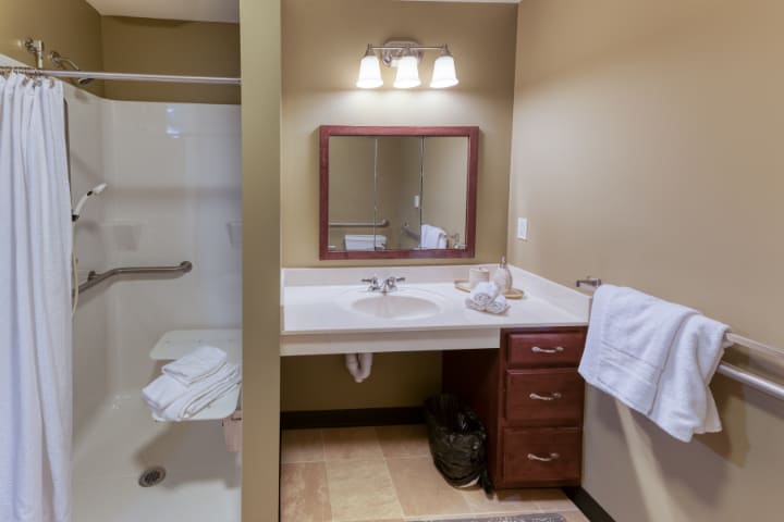 A well-lit bathroom with a sink, mirror, and shower area.
