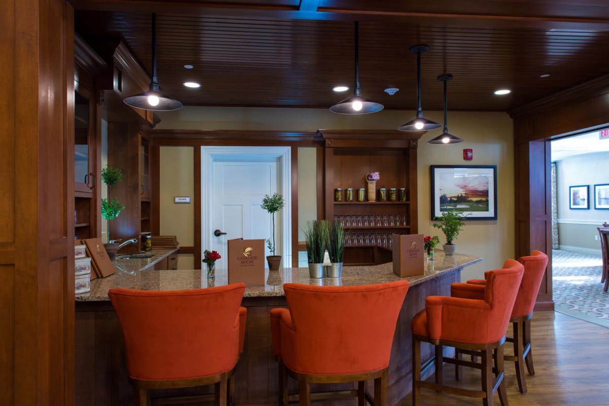 A cozy bar interior with bright orange chairs and warm lighting.