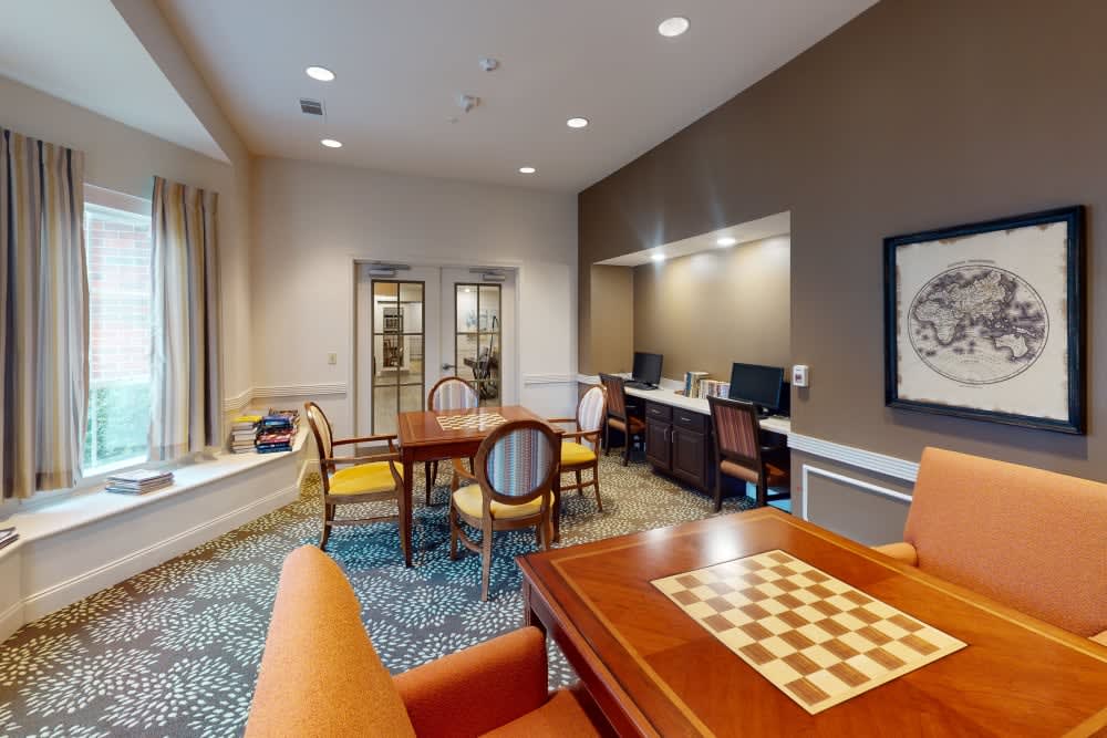 A cozy office space with a seating area, computer workstations, and a chess board.