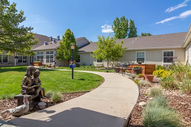 A well-maintained garden with a winding pathway leading to residential buildings on a sunny day.