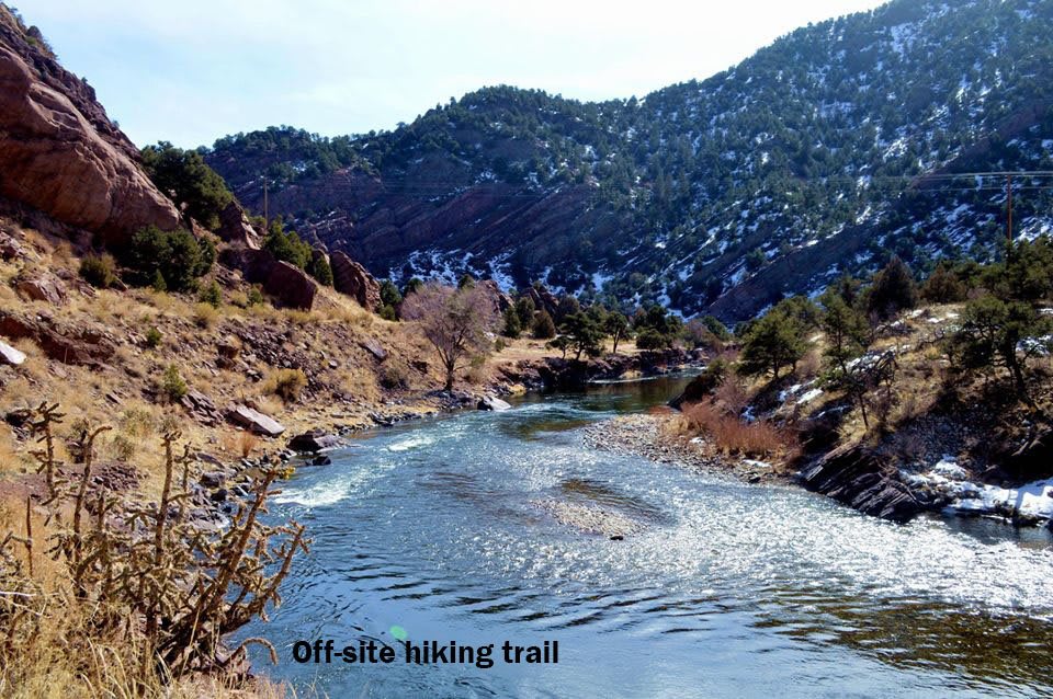 A scenic off-site hiking trail running alongside a river with mountainous landscape in the background.