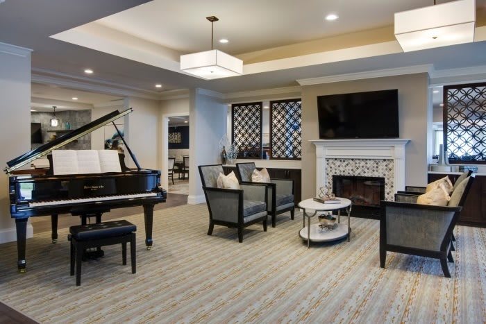 A modern living room featuring a grand piano, cozy seating area, and a fireplace with a wall-mounted television.