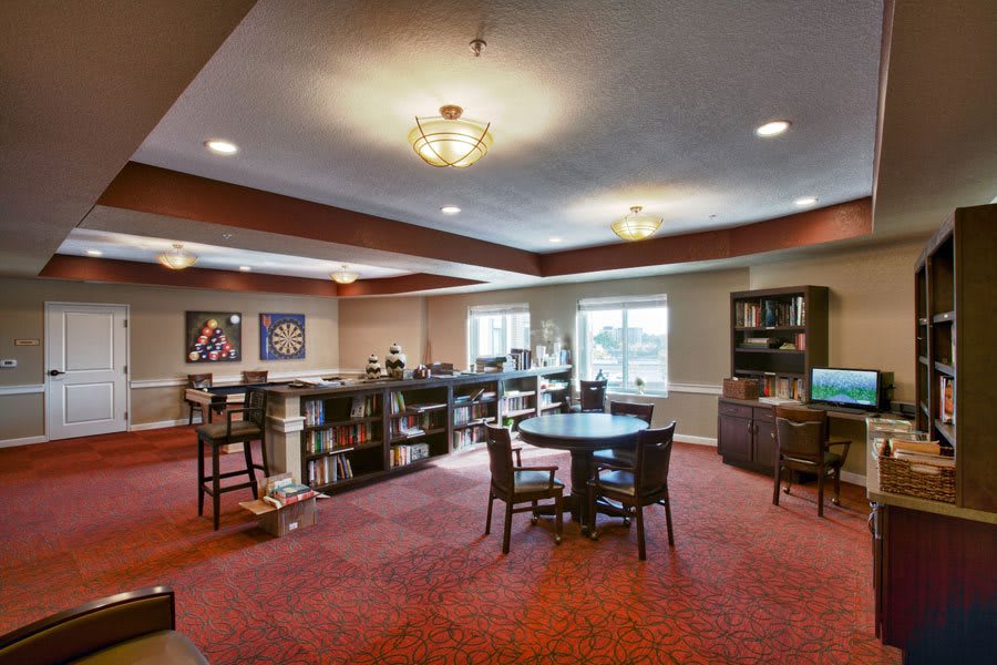 A spacious lounge area with tables, chairs, and bookshelves.