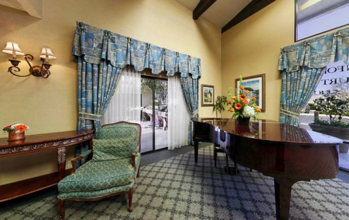A stylish living room with a grand piano, patterned curtains, and elegant furniture.