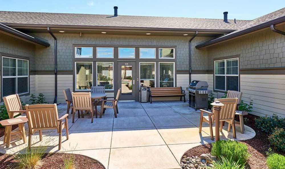 A backyard patio with outdoor seating and a barbecue grill on a sunny day.