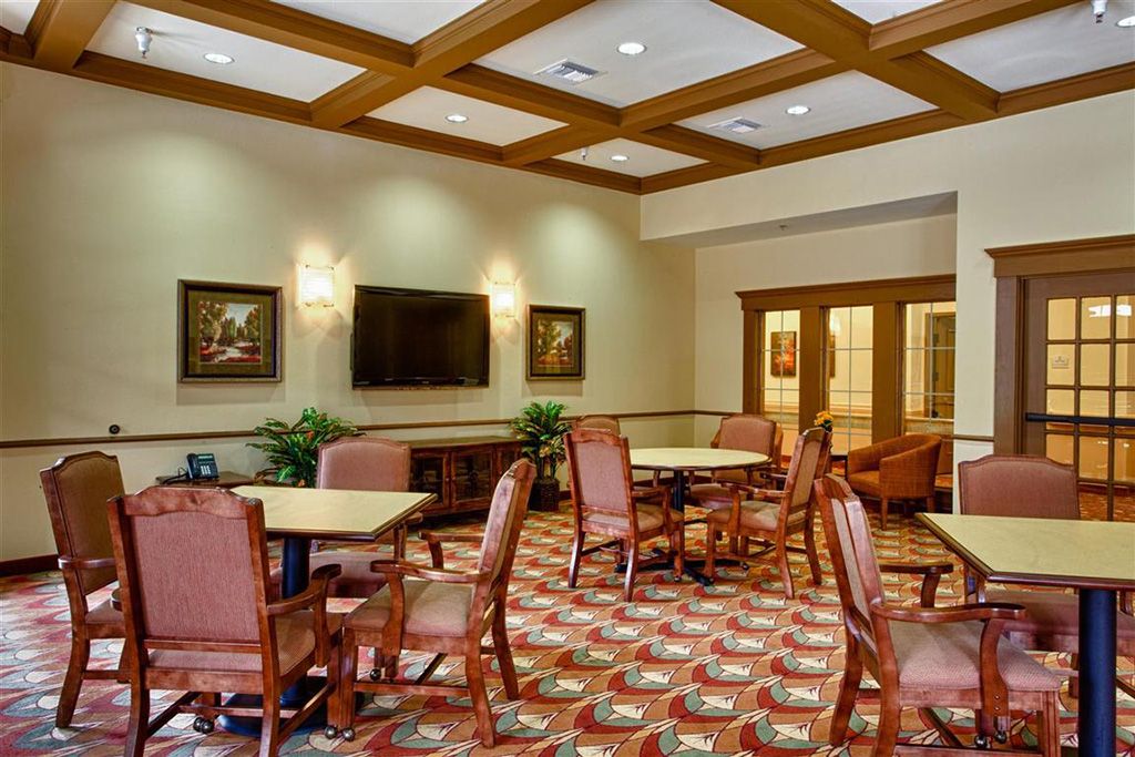 A well-furnished meeting room with tables and chairs, decorated with wall art and carpeted flooring.