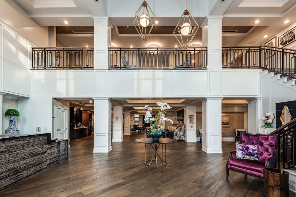 A spacious and elegant lobby featuring modern chandeliers, wood flooring, and stylish decor.