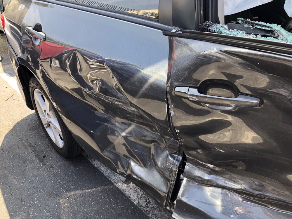 A car with significant damage to its side, showing dents and broken glass.