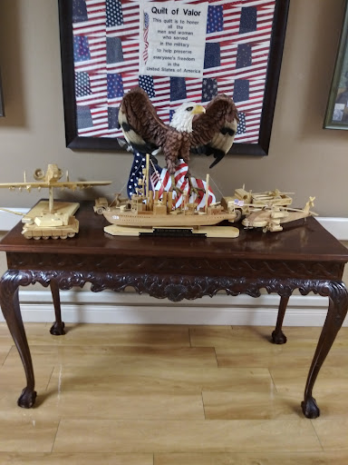 A patriotic display featuring intricately crafted wooden ship models and a majestic eagle sculpture atop a beautifully designed table.