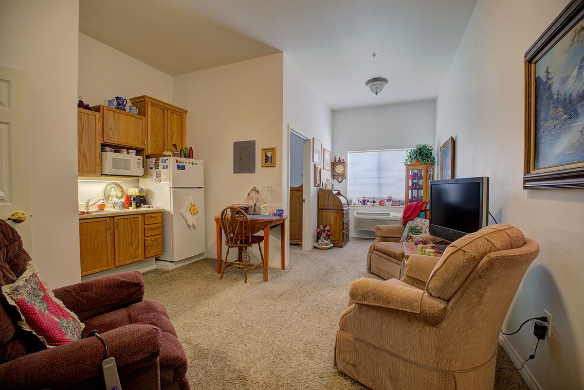 A cozy apartment living space featuring a small kitchen, dining area, and seating with a television.
