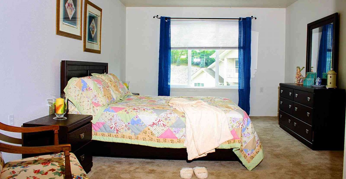 A cozy bedroom with colorful bedding and blue curtains.