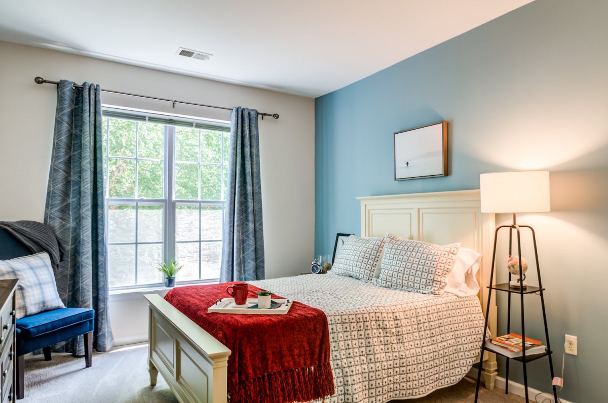 Cozy bedroom with a light blue accent wall and natural lighting.