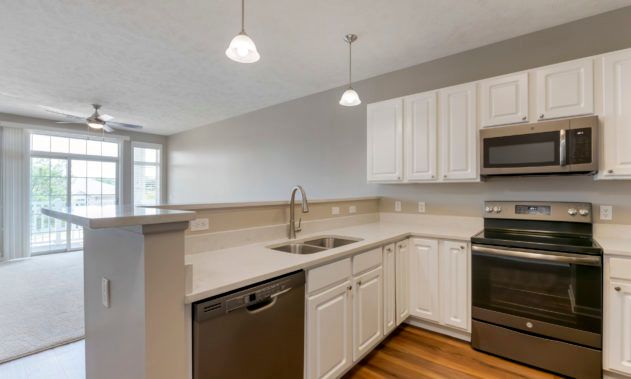 A modern kitchen featuring white cabinets, stainless steel appliances, and wooden flooring.