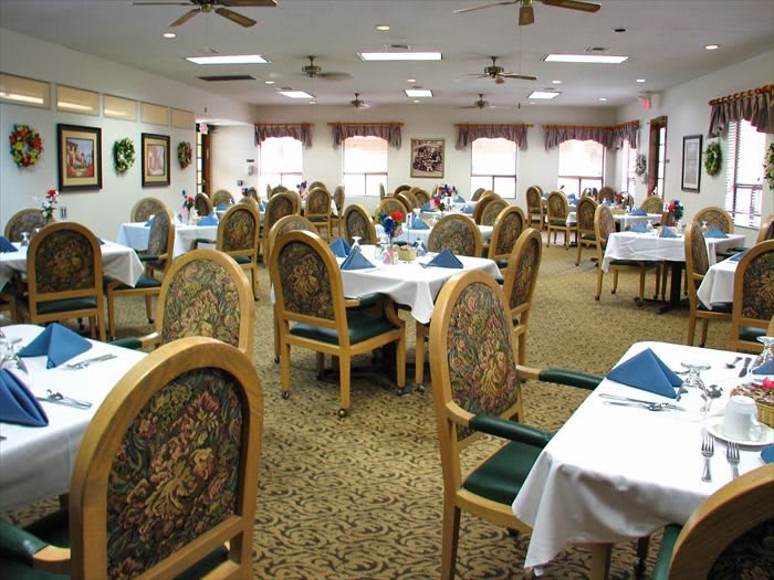 Spacious dining room with elegantly set tables and ornate chairs.