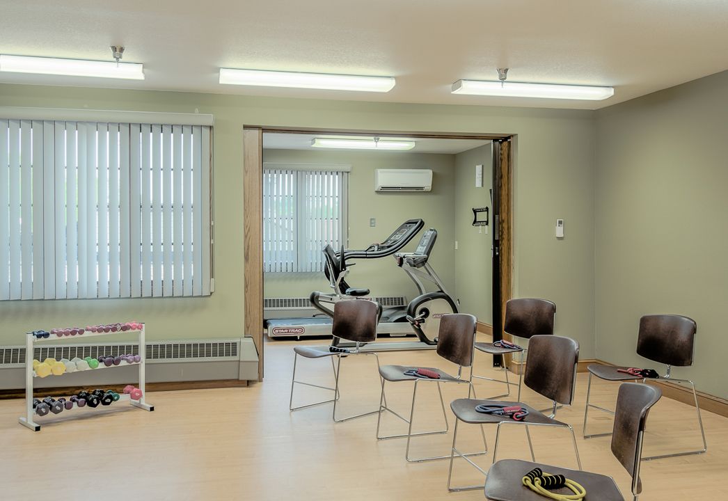 An interior view of an exercise room with multiple chairs and a stationary bike.