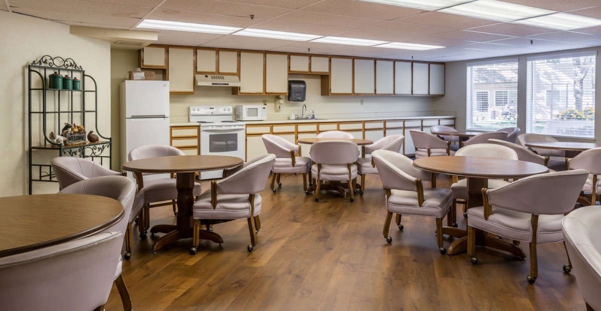A communal kitchen and dining area with round tables and comfortable chairs.