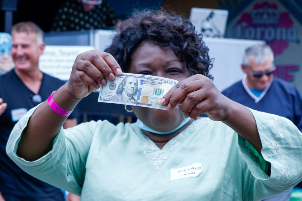 A woman holds up a banknote, examining it closely.