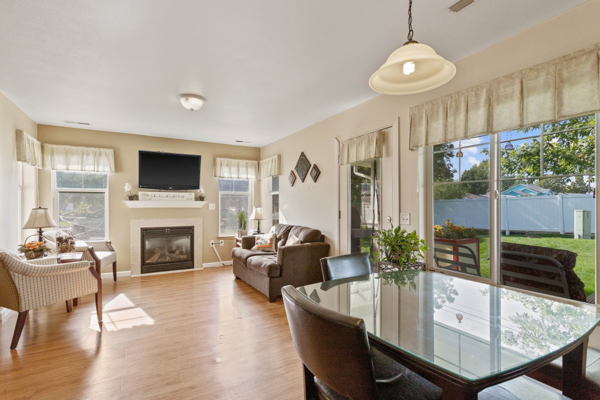 A modern living room with a fireplace and TV, adjacent to a dining area with ample natural light.