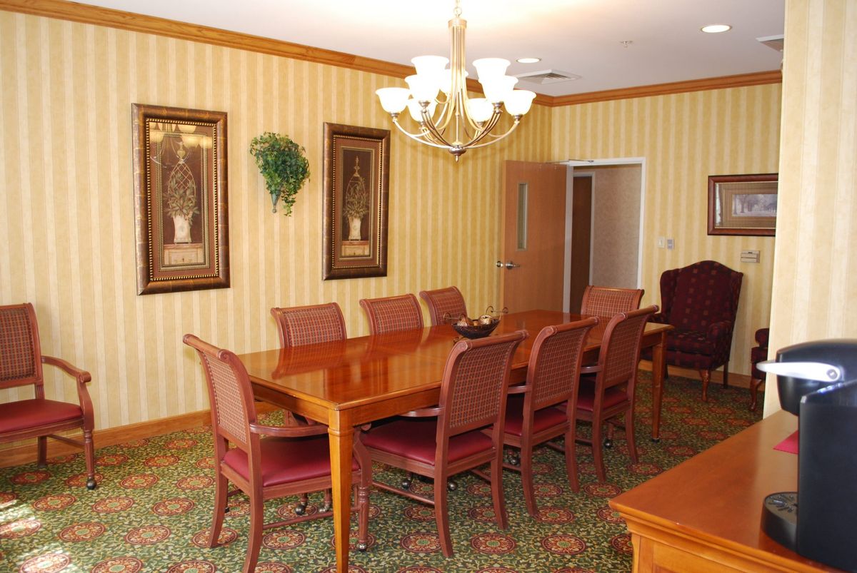 A formal dining room with a long wooden table and matching chairs under a chandelier.