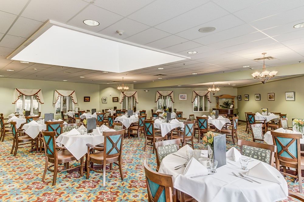 A well-decorated dining room with elegantly set tables and chairs, featuring patterned flooring and ambient lighting.