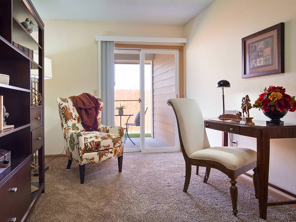 A cozy living room with a patterned armchair and elegant desk overlooking a balcony.