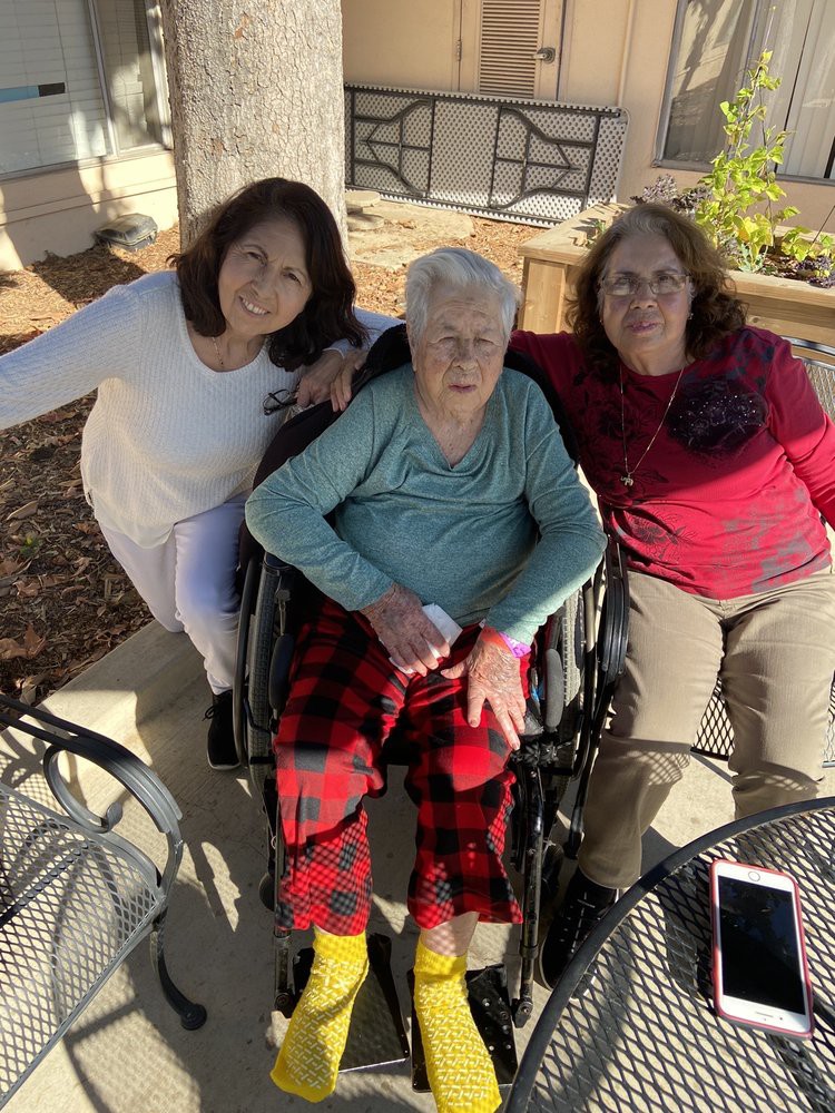Three people enjoying time together outdoors, with one person seated in a wheelchair.