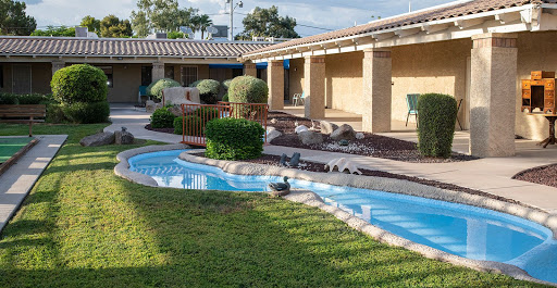 A serene courtyard featuring a winding water feature, lush greenery, and modern architectural elements.