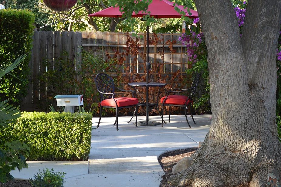 A tranquil backyard patio with red umbrella-shaded seating.